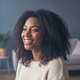 Headshot of a smiling woman in her late 20s, exuding contentment and trust, with a softly blurred background.